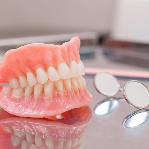 Fotografía referencial de prótesis removibles sobre una bandeja metálica con espejos dentales.
